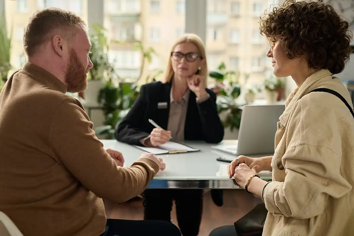 Back view portrait of adult couple consulting attorney in office settling health insurance for expats